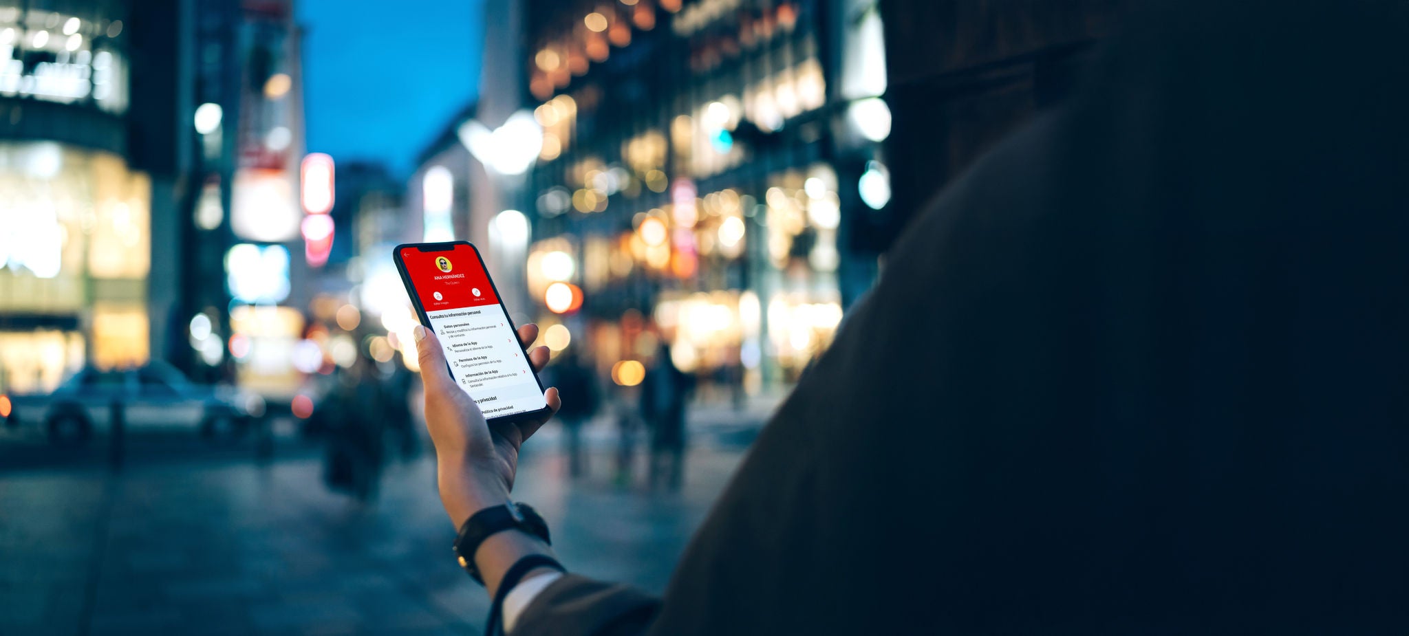 Santander mobile banking in use in a city at night